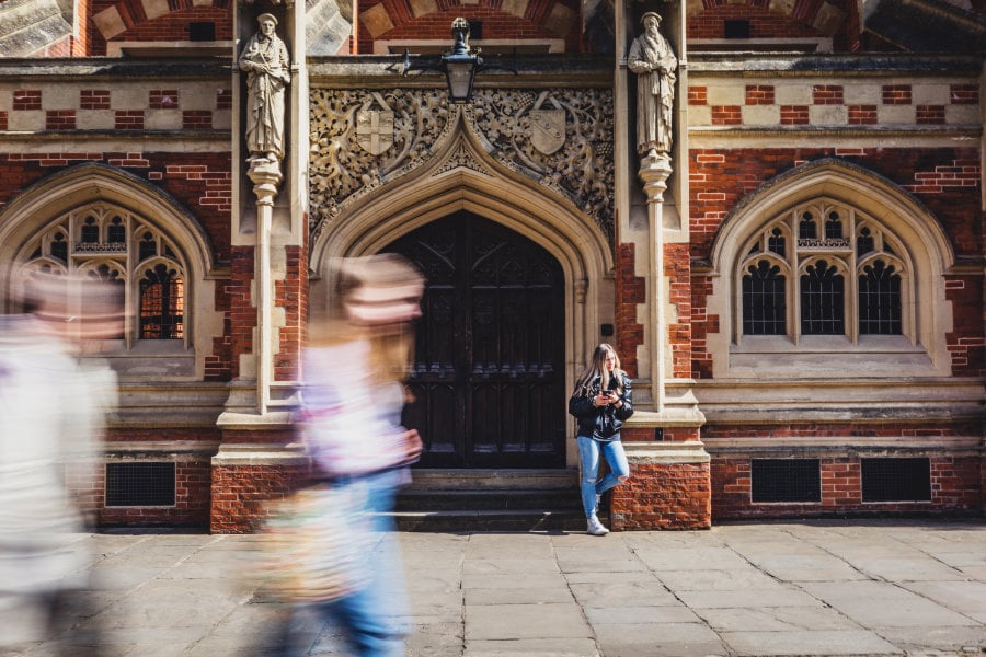  Long-exposure image showing women walking with motion blur in front of a large building<
