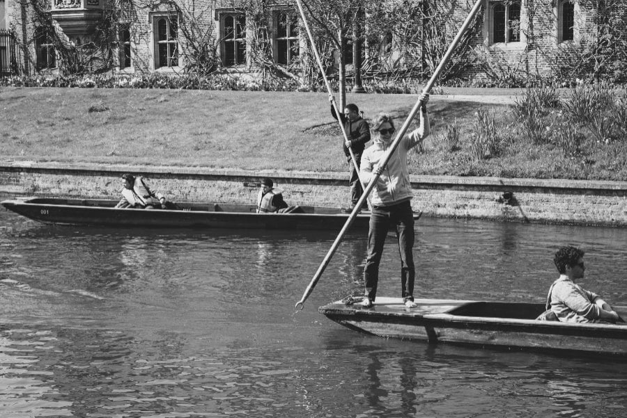  Photo of two gondolas passing on a river, with their punting poles forming an X<
