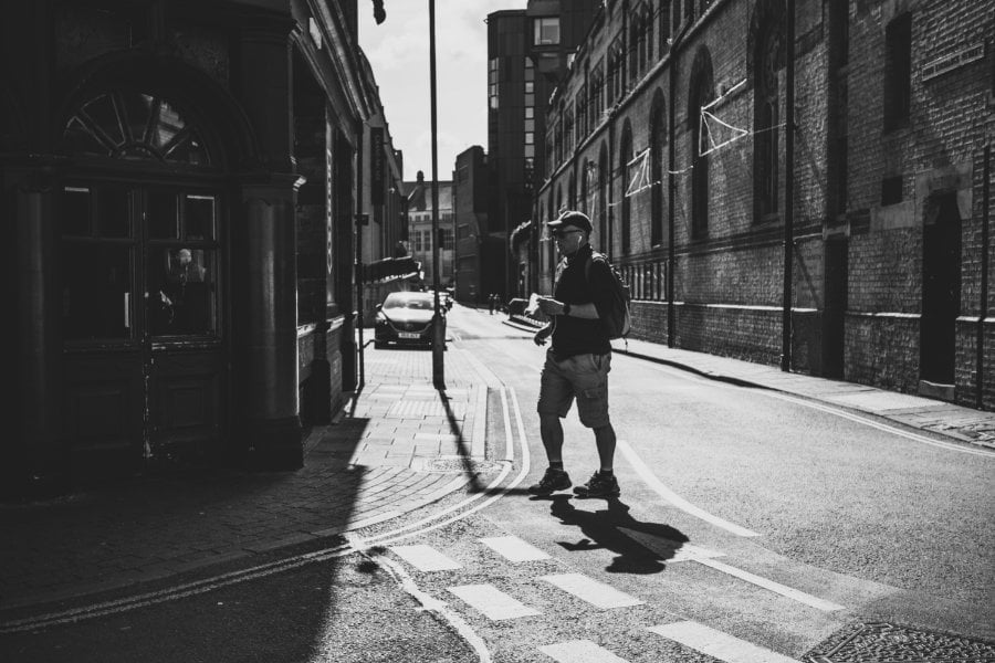 Monochrome photo of a man crossing a street<